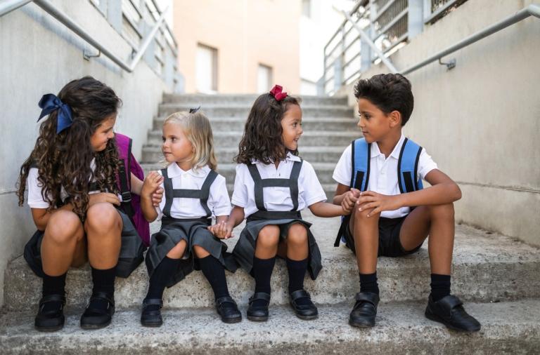 Young children sitting on a step in school uniform