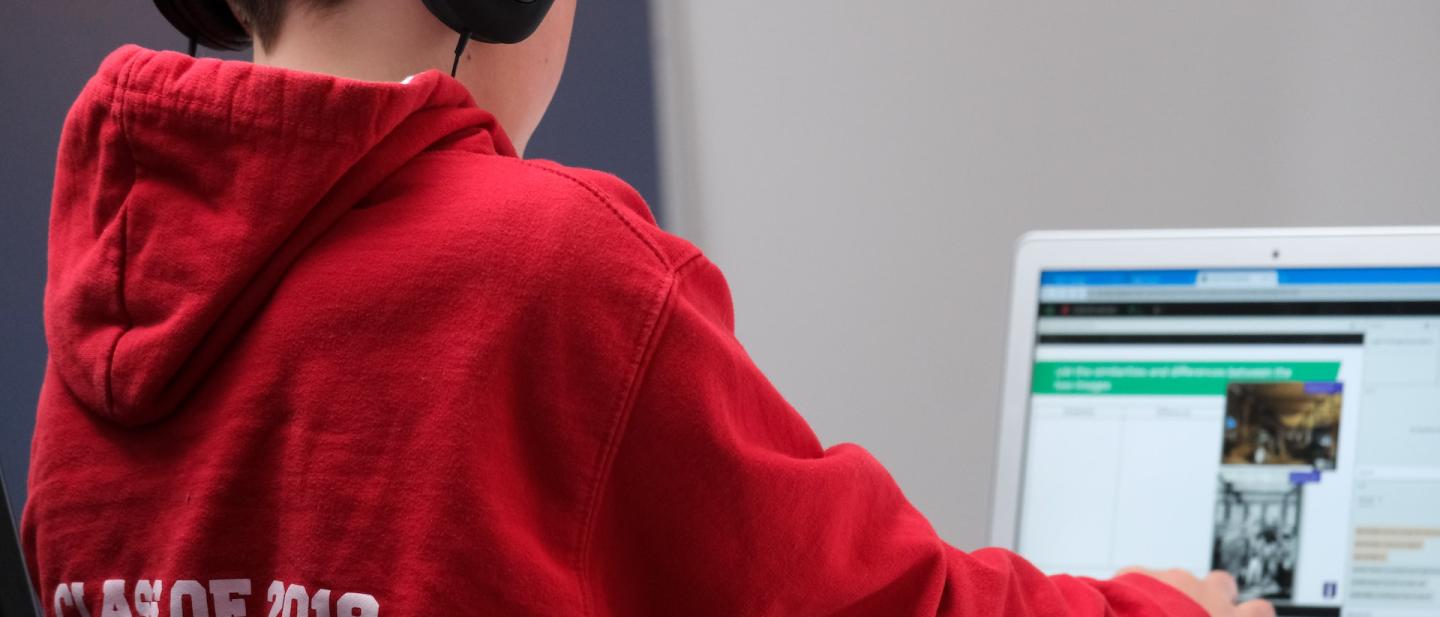 child learning and working on a laptop with headphones on