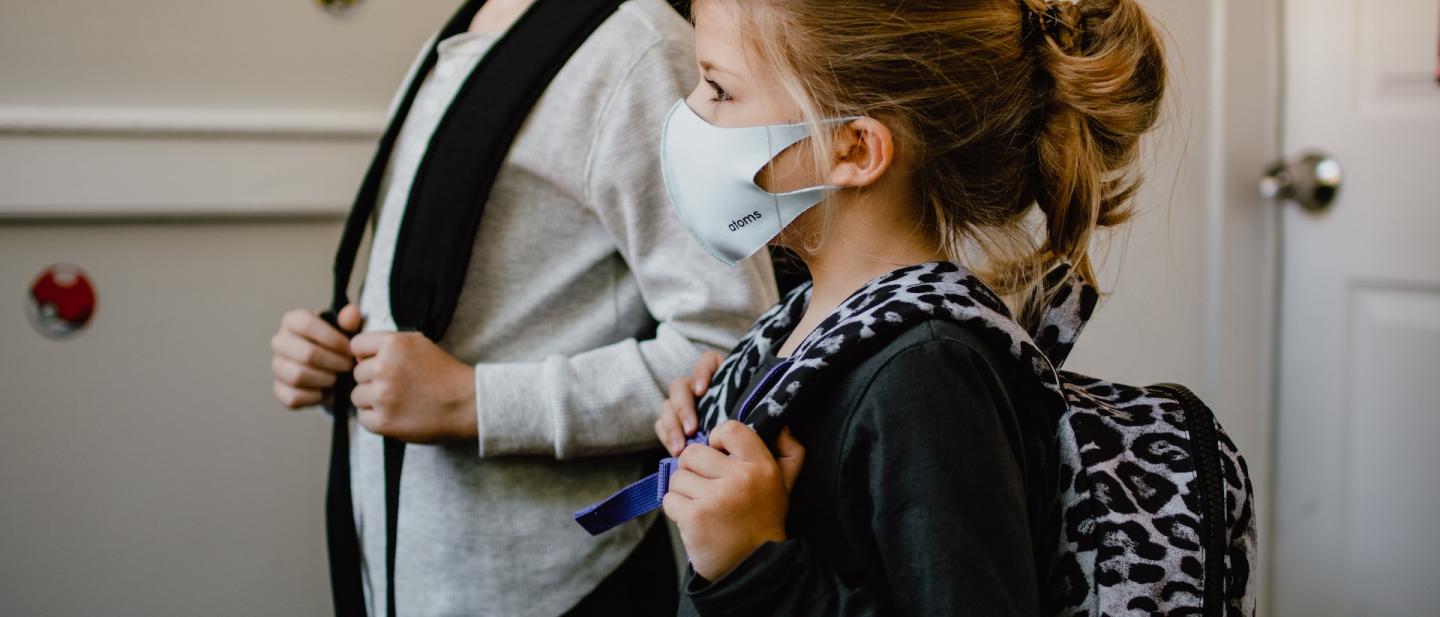 Children wearing face masks waiting to go into school