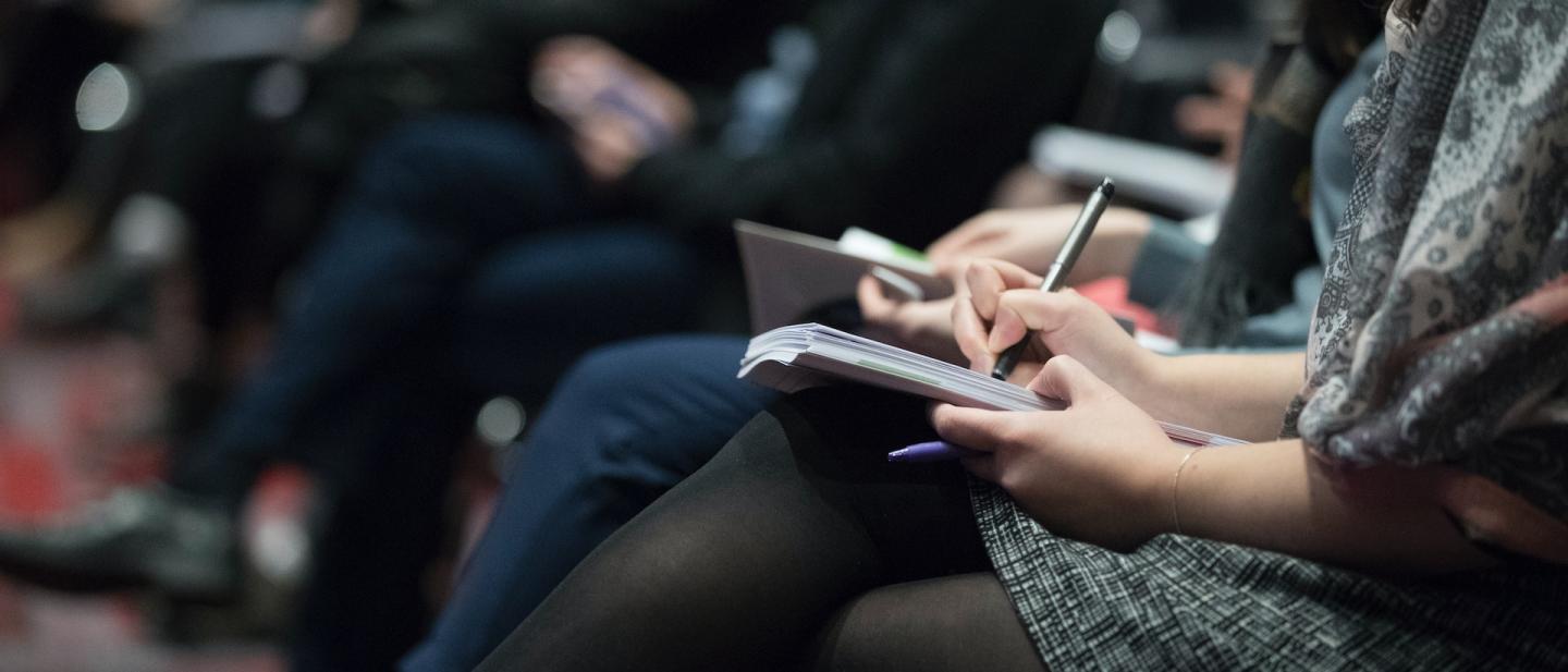 woman at a conference taking notes on her lap