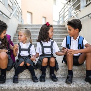 Young children sitting on a step in school uniform